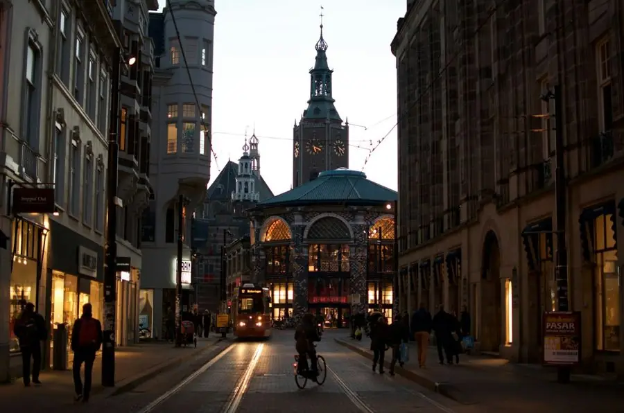 A tram and cyclists on a street in central The Hague at dusk