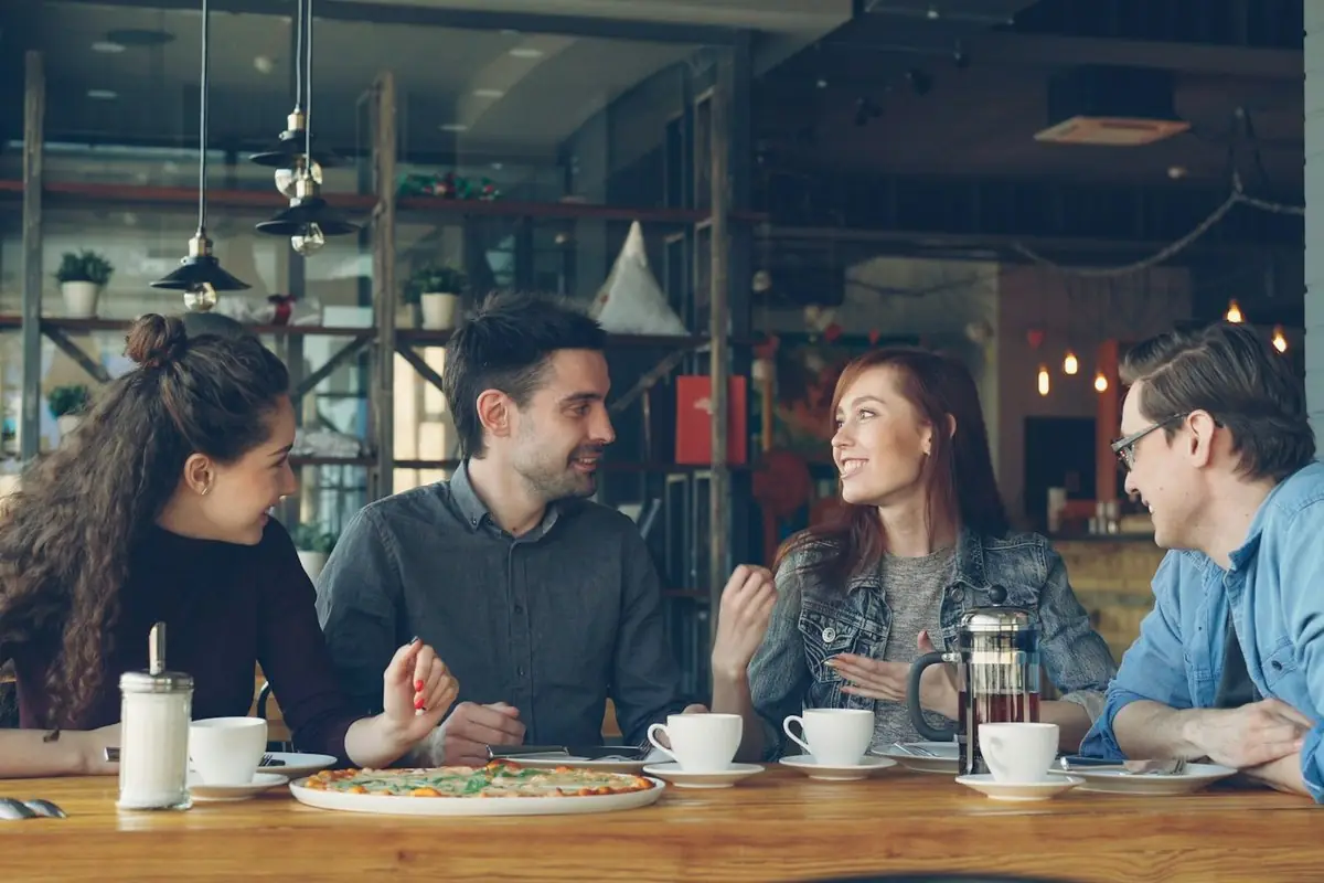 Een groep vrienden praat samen aan een café-tafel